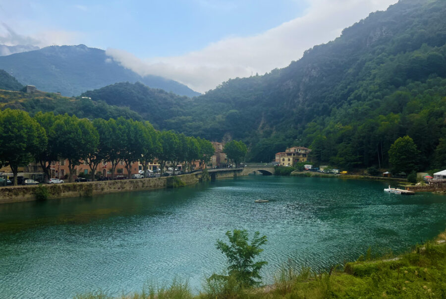 The lake of Breil-sur-Roya, surrounded by mountains, village houses and a stone bridge in the Roya Valley.