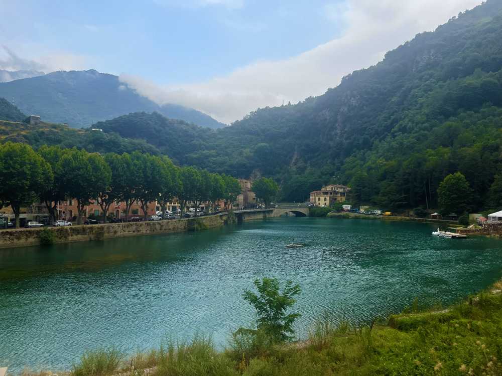 The lake of Breil-sur-Roya, surrounded by mountains, village houses and a stone bridge in the Roya Valley.