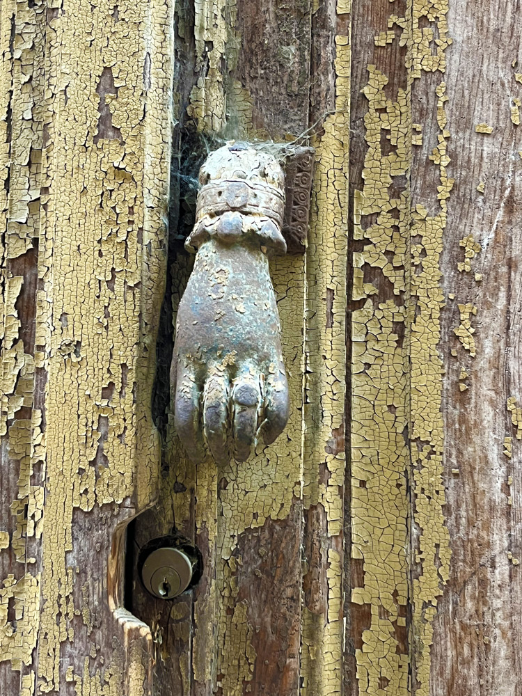 Old hand-shaped door knocker on a weathered wooden door in Breil-sur-Roya.